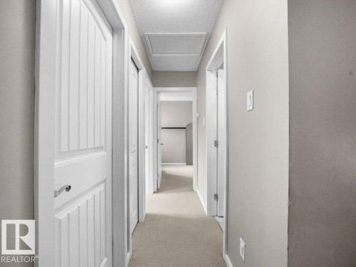 Carpeted hallway with light-toned walls and white paneled doors - 34 Amberly Court Nw, Edmonton, AB - Indoor Photo Showing Other Room