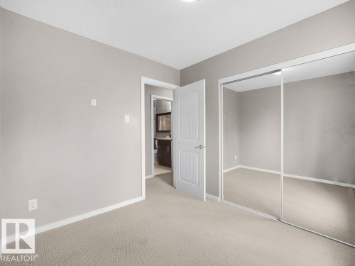 Neutral wall color, carpeted flooring, mirrored sliding closet doors, and a paneled interior door - 34 Amberly Court Nw, Edmonton, AB - Indoor Photo Showing Other Room