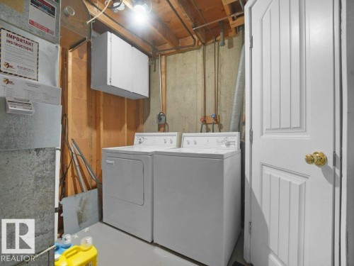Laundry area featuring a washer and dryer, exposed ceiling joists, and a paneled door - 34 Amberly Court Nw, Edmonton, AB - Indoor Photo Showing Laundry Room