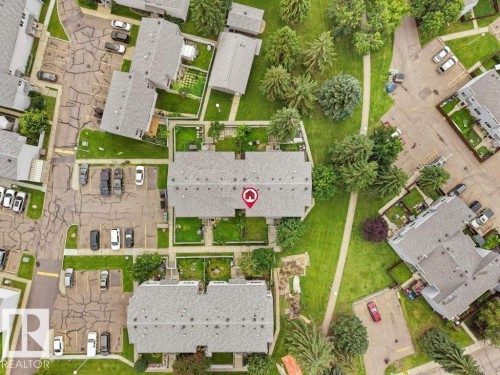 Townhome structure with a gray shingled roof, individual fenced yard spaces, and surrounding green space - 34 Amberly Court Nw, Edmonton, AB - 
