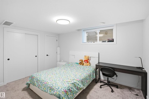 Bright basement bedroom featuring neutral carpeting, recessed ceiling lighting, and casement windows with blinds - 5493 Kootook Road Sw, Edmonton, AB - Indoor Photo Showing Bedroom