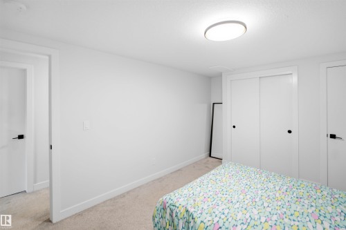 Recessed lighting, light-toned carpeting, white walls, and a sliding door closet with black hardware - 5493 Kootook Road Sw, Edmonton, AB - Indoor Photo Showing Bedroom