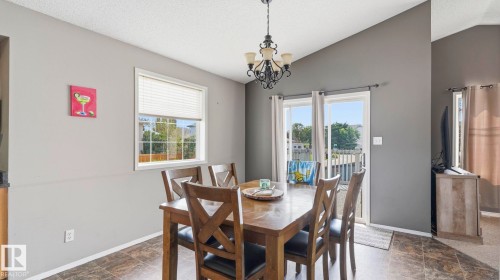 Dining area featuring vaulted ceilings, a decorative chandelier, and tile-look flooring - 4105 36A Avenue Nw, Edmonton, AB - Indoor Photo Showing Dining Room