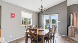 Dining area featuring vaulted ceilings, a decorative chandelier, and tile-look flooring - 