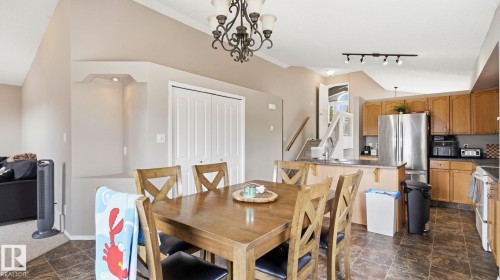 Dining area with a wrought iron chandelier, built-in display niche with lighting, and double bi-fold closet doors - 4105 36A Avenue Nw, Edmonton, AB - Indoor Photo Showing Dining Room