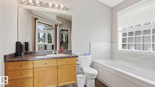 Bathroom featuring a light wood-finish vanity with an integrated sink, a large mirror, and overhead vanity lighting - 4105 36A Avenue Nw, Edmonton, AB - Indoor Photo Showing Bathroom