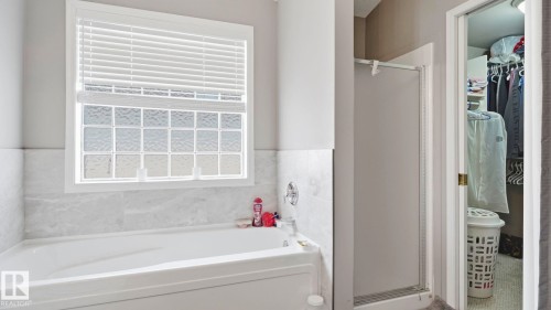 Soaking tub with a white tile surround, glass block window, and a separate shower enclosure - 4105 36A Avenue Nw, Edmonton, AB - Indoor Photo Showing Bathroom