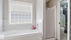 Soaking tub with a white tile surround, glass block window, and a separate shower enclosure - 
