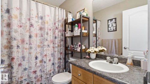 Bathroom featuring a single vanity with an integrated sink, dark countertop, and wood-finish cabinetry - 4105 36A Avenue Nw, Edmonton, AB - Indoor Photo Showing Bathroom