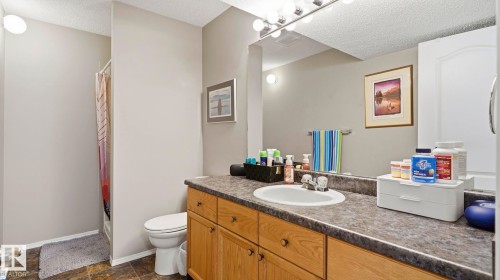 Bathroom vanity featuring a single basin sink, a durable countertop, and wood-finish cabinetry providing ample storage - 4105 36A Avenue Nw, Edmonton, AB - Indoor Photo Showing Bathroom
