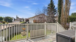 Spacious outdoor deck with white railing, overlooking a fenced backyard with green lawn - 