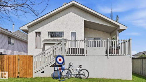 Rear exterior with a stucco finish, featuring a second-story deck with vertical railings and a staircase leading to the ground level - 4105 36A Avenue Nw, Edmonton, AB - Outdoor