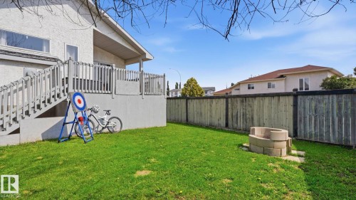 Spacious rear yard featuring a raised deck with stairs, a stone block fire pit, and a partial privacy fence - 4105 36A Avenue Nw, Edmonton, AB - Outdoor