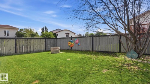 Expansive backyard featuring a lush lawn, privacy fencing, and a built-in stone fire pit - 4105 36A Avenue Nw, Edmonton, AB - Outdoor