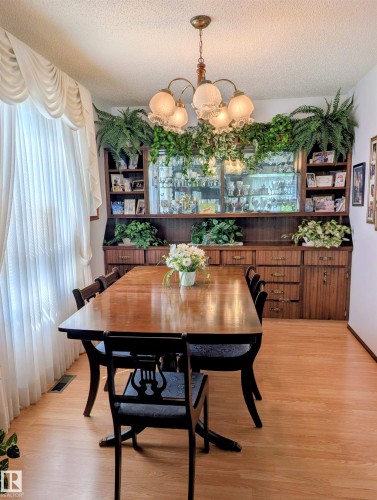Built-in wood cabinetry with glass-front display, overhead lighting, and integrated storage - 6014 50 Street, Vegreville, AB - Indoor Photo Showing Dining Room