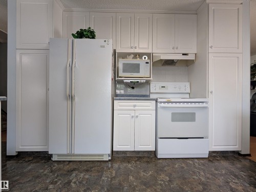 White panel cabinetry and white appliances, including a refrigerator, range, and microwave - 6014 50 Street, Vegreville, AB - Indoor Photo Showing Kitchen