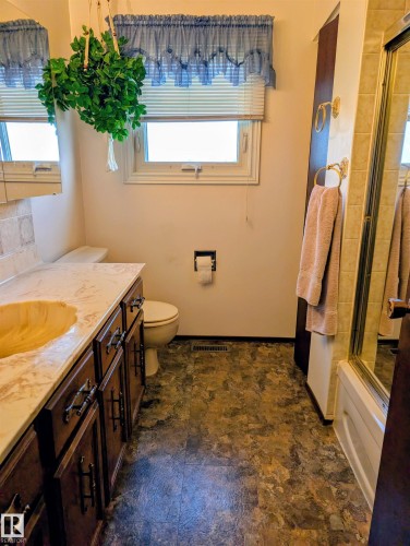 Bathroom featuring a built-in vanity with a countertop and integrated sink, a toilet, and a shower with a glass enclosure - 6014 50 Street, Vegreville, AB - Indoor Photo Showing Bathroom