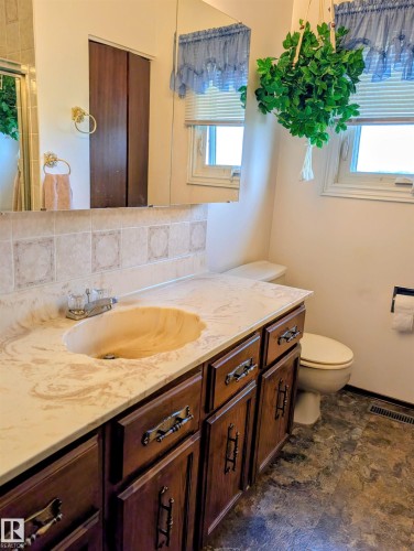 Vanity with integrated sink, wood-finish cabinetry, and decorative hardware - 6014 50 Street, Vegreville, AB - Indoor Photo Showing Bathroom