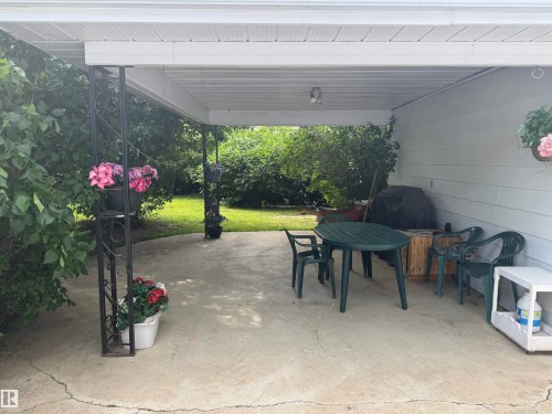 Covered concrete patio with white siding and metal support columns - 6014 50 Street, Vegreville, AB - Outdoor