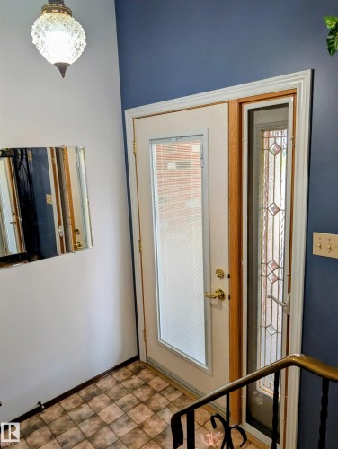 Entryway featuring a decorative glass pendant light, patterned floor tile, and a door with a frosted glass panel and sidelight - 6014 50 Street, Vegreville, AB - Indoor Photo Showing Other Room