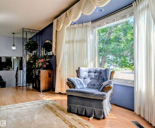 Expansive window with sheer and drapery treatments, recessed lighting, wood-finish flooring, and decorative metalwork partition - 6014 50 Street, Vegreville, AB - Indoor Photo Showing Living Room