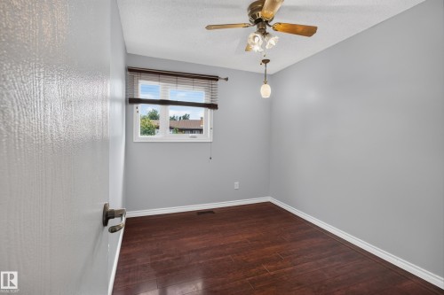 Hardwood-finish flooring with white trim, a single window with blinds, and an overhead ceiling fan with light fixture - 2011 151 Avenue Nw, Edmonton, AB - Indoor Photo Showing Other Room