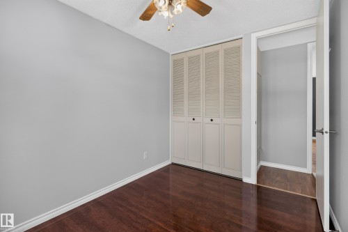 Wood-finish flooring, louvered bi-fold closet doors, and a ceiling fan with integrated lighting - 2011 151 Avenue Nw, Edmonton, AB - Indoor Photo Showing Other Room