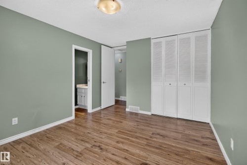 Wood-finish flooring, white bi-fold closet doors, white baseboards, and a neutral wall color - 2011 151 Avenue Nw, Edmonton, AB - Indoor Photo Showing Other Room