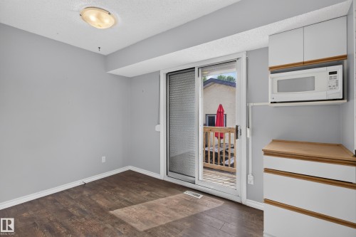 Wood-finish flooring, sliding glass door, built-in microwave, white cabinetry, and wood-finish countertops - 2011 151 Avenue Nw, Edmonton, AB - Indoor Photo Showing Other Room