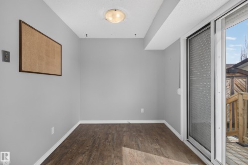Wood-finish flooring, white trim, sliding glass door, overhead flush-mount lighting, and light gray wall color - 2011 151 Avenue Nw, Edmonton, AB - Indoor Photo Showing Other Room
