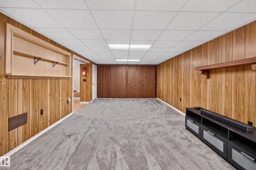 Spacious finished basement featuring wood-paneled walls, neutral carpet flooring, recessed ceiling lighting, and built-in cabinetry - 2011 151 Avenue Nw, Edmonton, AB - Indoor