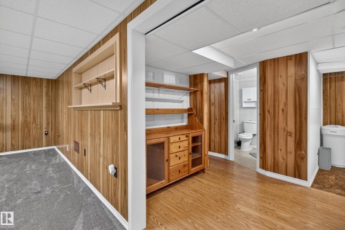 Wood-finish wall paneling, built-in shelving, wood-finish flooring, and a built-in wooden cabinet with glass doors - 2011 151 Avenue Nw, Edmonton, AB - Indoor Photo Showing Other Room