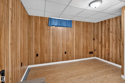 Finished basement room featuring wood-finish wall paneling, engineered wood flooring, recessed ceiling lighting, and multiple electrical outlets - 2011 151 Avenue Nw, Edmonton, AB - Indoor Photo Showing Other Room