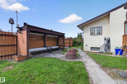 Expansive yard featuring a concrete pathway, a built-in fire pit, and a covered wooden pergola with built-in seating - 2011 151 Avenue Nw, Edmonton, AB - Outdoor With Exterior