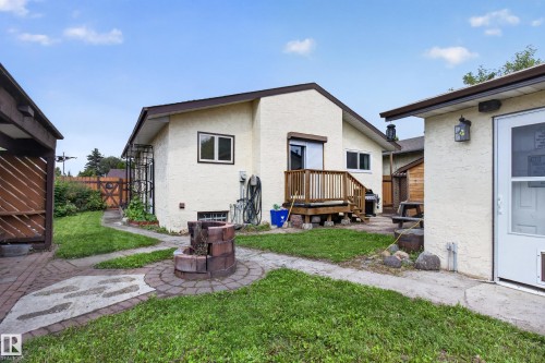 Expansive backyard featuring a wood deck, brick fire pit, and paved pathways - 2011 151 Avenue Nw, Edmonton, AB - Outdoor With Exterior