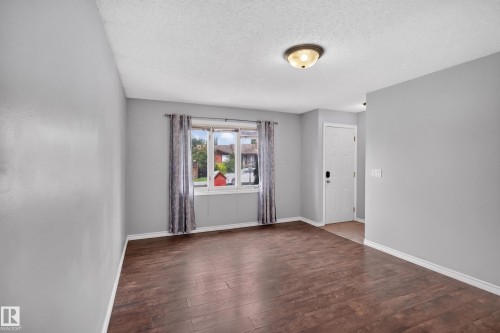 Spacious room featuring wood-finish flooring, light gray walls, and a multi-pane window - 2011 151 Avenue Nw, Edmonton, AB - Indoor Photo Showing Other Room