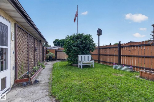 Expansive grassy yard area with a concrete pathway and wood fencing - 2011 151 Avenue Nw, Edmonton, AB - Outdoor