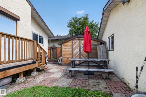 Wood deck with railings and stairs, a paved patio with brick and concrete pavers, and a wood storage shed - 2011 151 Avenue Nw, Edmonton, AB - Outdoor With Exterior