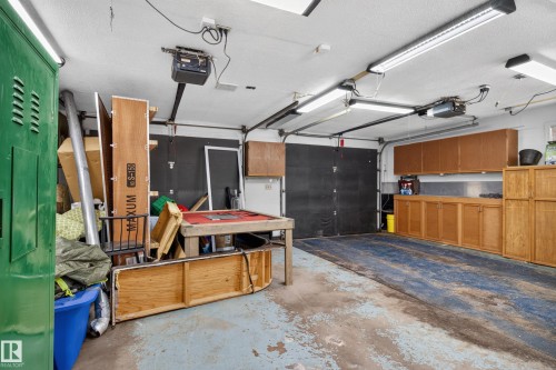 Garage space with overhead fluorescent lighting, built-in cabinetry, and overhead door - 2011 151 Avenue Nw, Edmonton, AB - Indoor Photo Showing Garage
