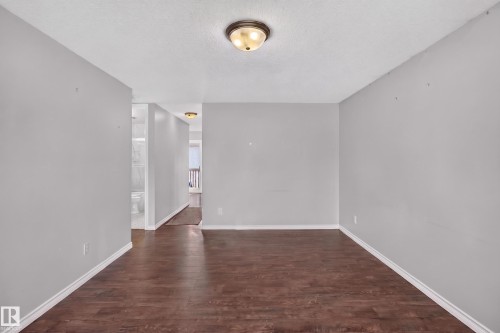 Expansive open room featuring wood-finish flooring, light gray walls, and a ceiling-mounted light fixture - 2011 151 Avenue Nw, Edmonton, AB - Indoor Photo Showing Other Room