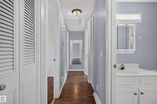 Hallway featuring wood-finish flooring, light blue wall paint, and white trim - 2011 151 Avenue Nw, Edmonton, AB - Indoor