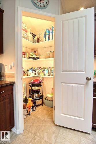Walk-in pantry with built-in shelving, tile flooring, and white panel door - 417 Oak Wood Crescent Northwest, Edmonton, AB - Indoor Photo Showing Other Room