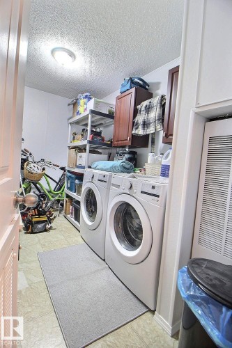 Laundry area with front-loading washer and dryer, tile-look flooring, and ceiling-mounted light fixture - 417 Oak Wood Crescent Northwest, Edmonton, AB - Indoor Photo Showing Laundry Room