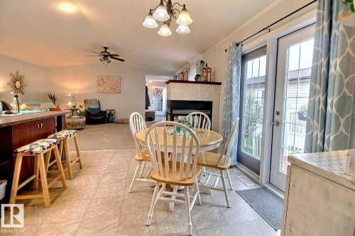 Tiled flooring, recessed lighting, and a chandelier illuminate the dining area - 417 Oak Wood Crescent Northwest, Edmonton, AB - Indoor Photo Showing Dining Room With Fireplace