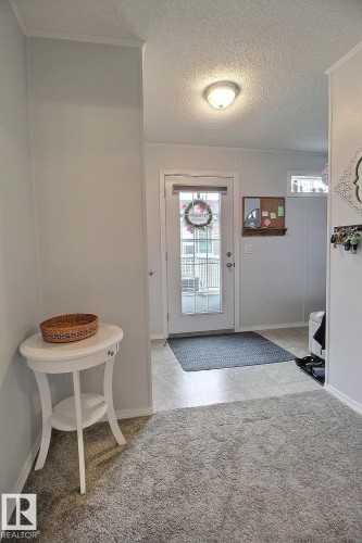 Entryway featuring a white door with a glass panel, overhead flush-mount lighting, and durable tile flooring leading to plush carpeting - 417 Oak Wood Crescent Northwest, Edmonton, AB - Indoor Photo Showing Other Room