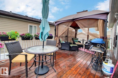Expansive wood deck with a built-in gazebo featuring privacy screens, a glass-top table, and a white railing with attached planters - 417 Oak Wood Crescent Northwest, Edmonton, AB - Outdoor With Deck Patio Veranda With Exterior