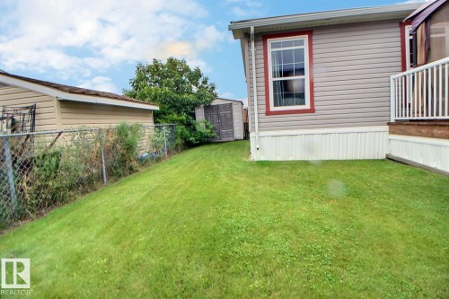 Expansive green lawn with a chain-link fence, siding exterior, and a built-in deck featuring white railings - 417 Oak Wood Crescent Northwest, Edmonton, AB - Outdoor