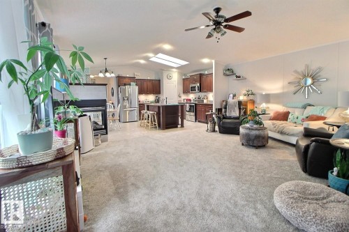 Open concept living area featuring a kitchen with wood-finish cabinetry, a central island, and stainless steel appliances - 417 Oak Wood Crescent Northwest, Edmonton, AB - Indoor Photo Showing Other Room