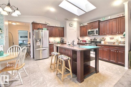 Kitchen with an island, dark wood-finish cabinetry, stainless steel appliances, and a skylight - 417 Oak Wood Crescent Northwest, Edmonton, AB - Indoor Photo Showing Kitchen With Stainless Steel Kitchen With Upgraded Kitchen