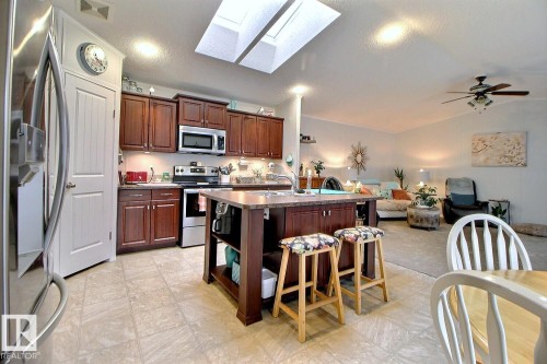 Kitchen with wood-finish cabinetry, stainless steel appliances, and a central island with a sink - 417 Oak Wood Crescent Northwest, Edmonton, AB - Indoor Photo Showing Kitchen With Stainless Steel Kitchen